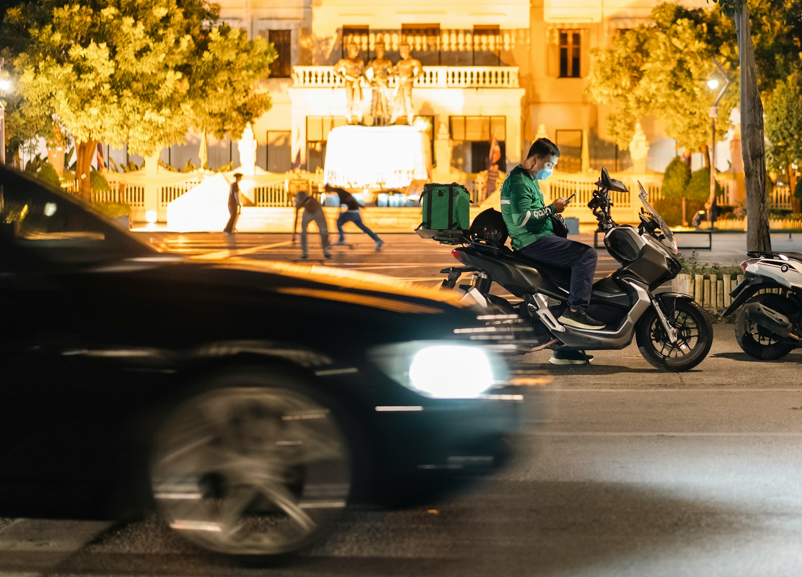 a man riding a motorcycle down a street next to a car